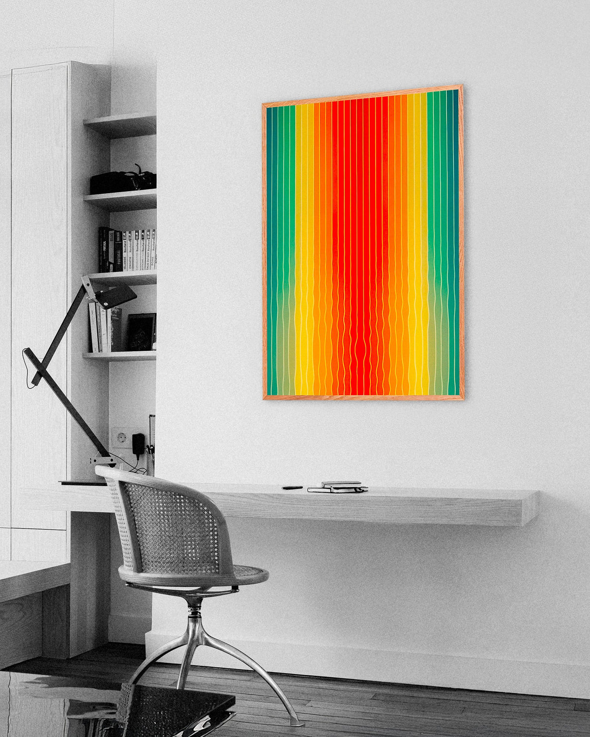 Home office with a floating desk, a cane chair and an oak-framed poster of vertical rainbow stripes in green, yellow and red