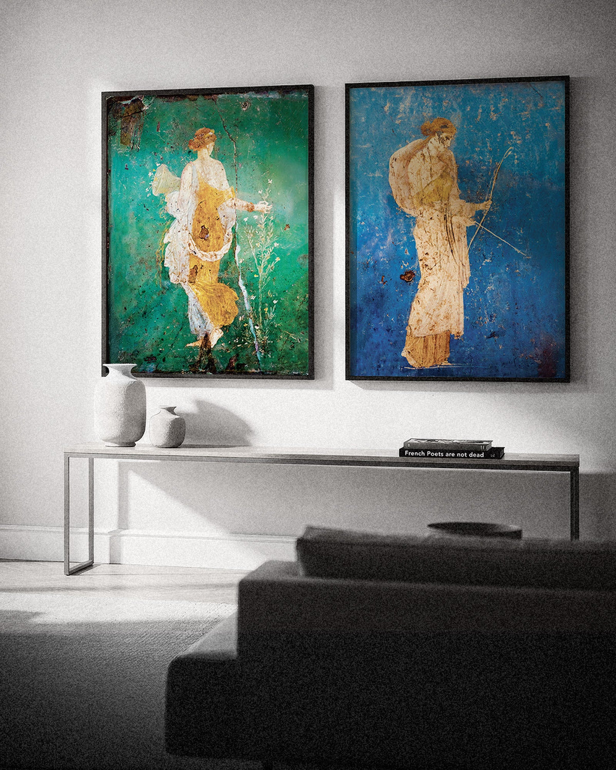 Two framed Pompeii fresco posters, Flora on green and Artemis on blue, above a console table in a living room