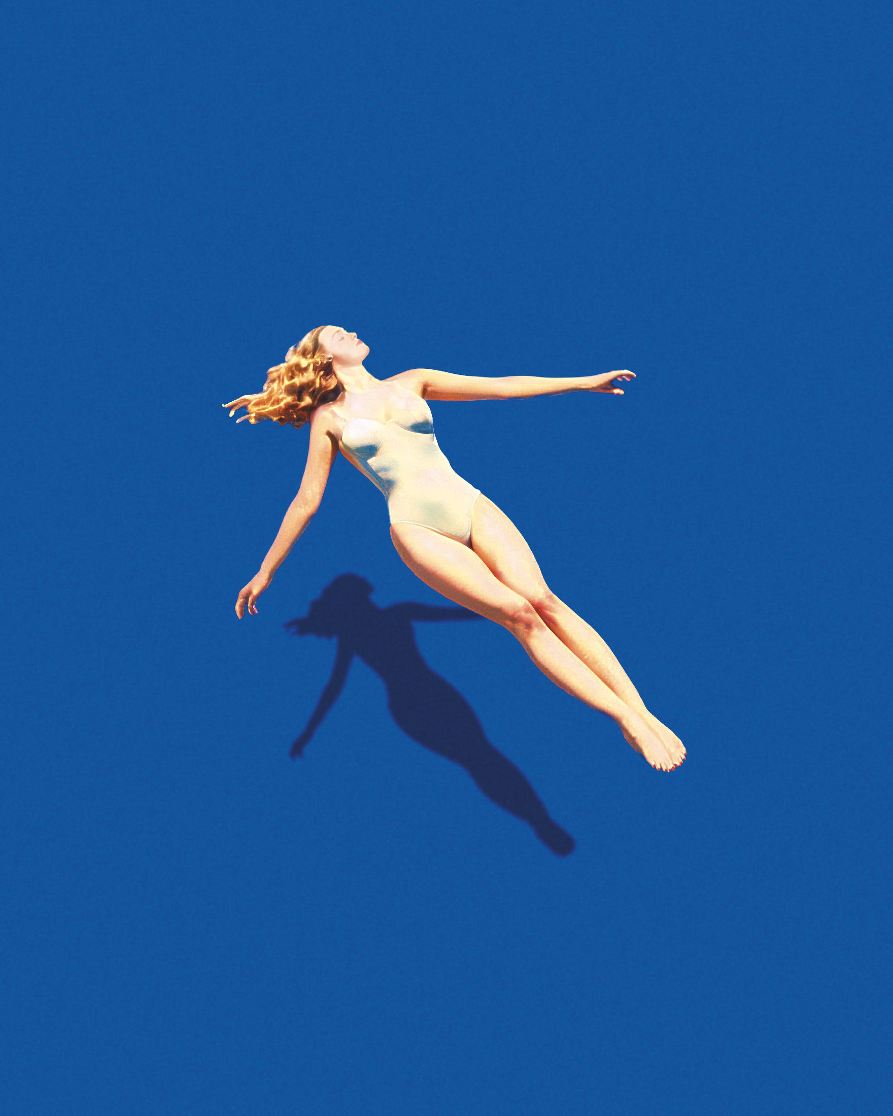 Woman in a white swimsuit floating against a blue background